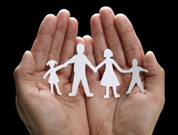 A picture of a person holding a white paper cutout of a a family in their hands. 